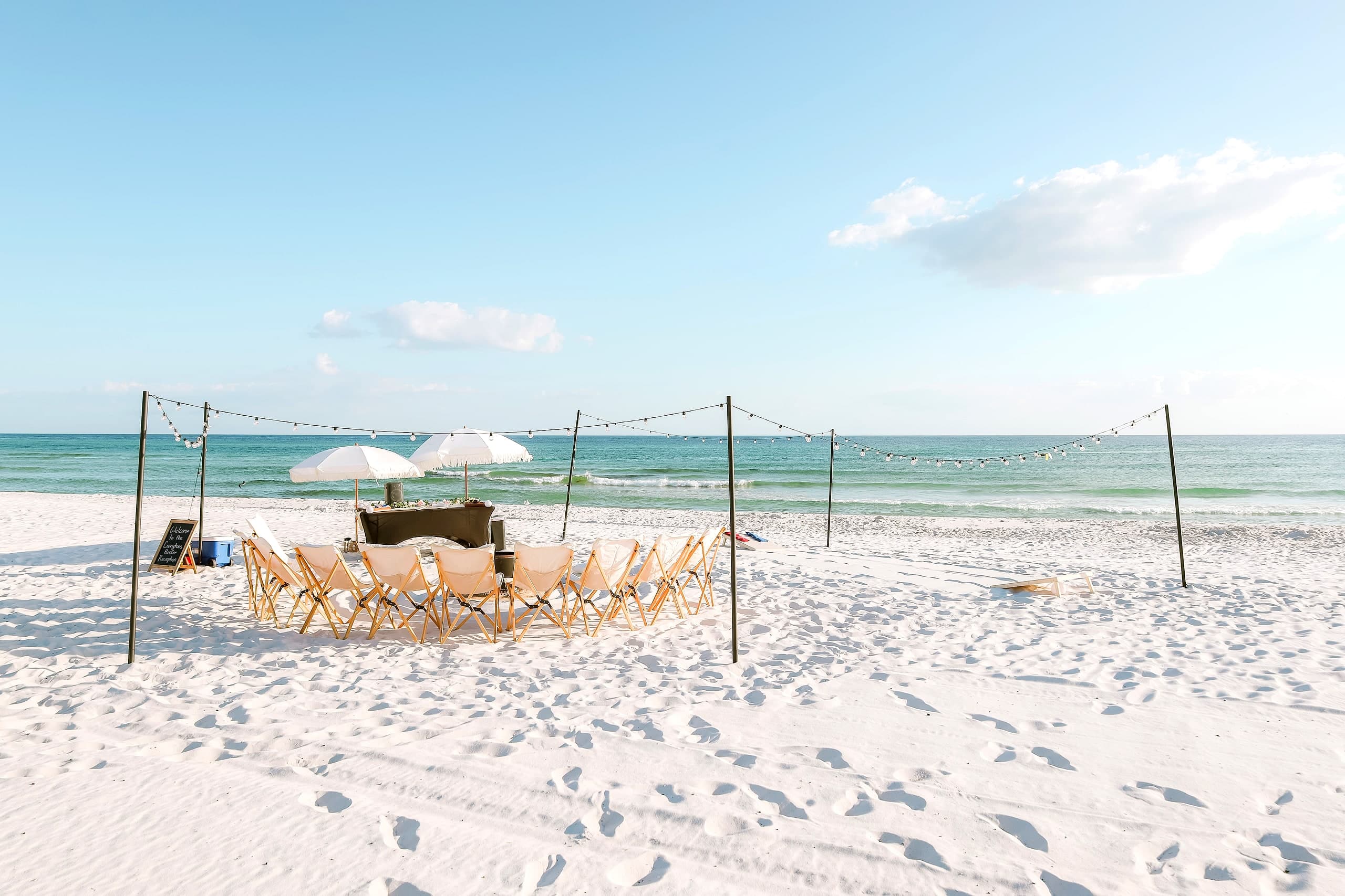 An elevated beach bonfire styled at sunset with chairs, tiki torches and a fire on the white sand of 30A