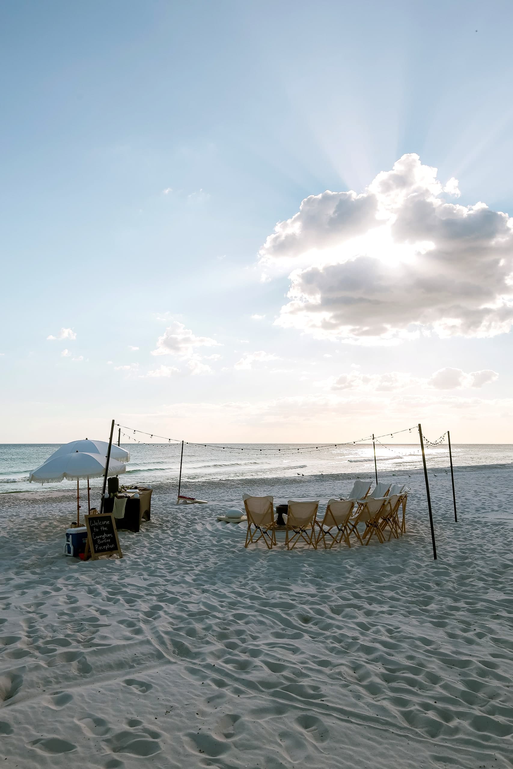 A styled beach bonfire setup glowing under string lights and golden light on 30A
